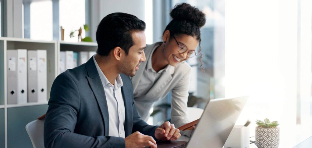 two finance professionals look at a computer together